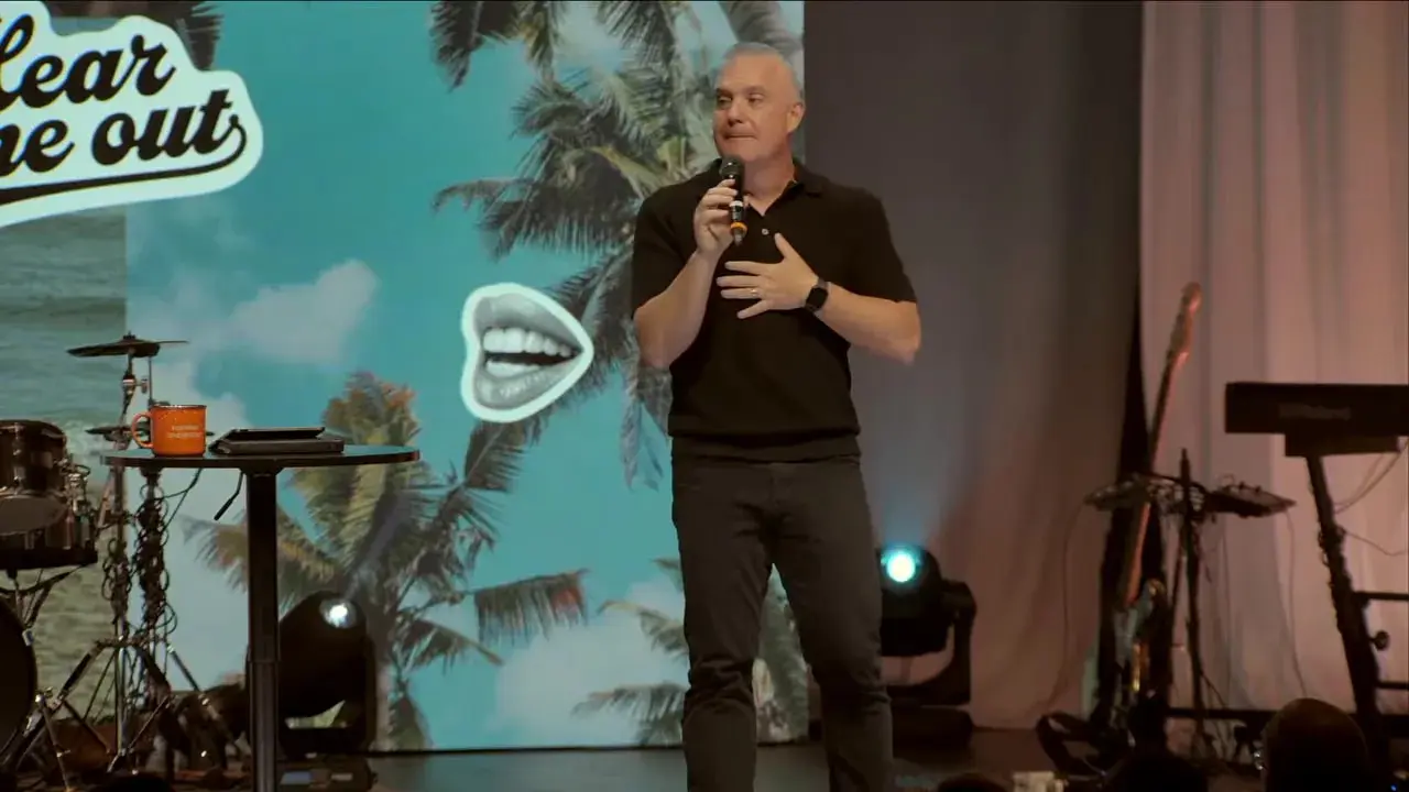 Speaker on stage reaching outward while speaking, clear composition